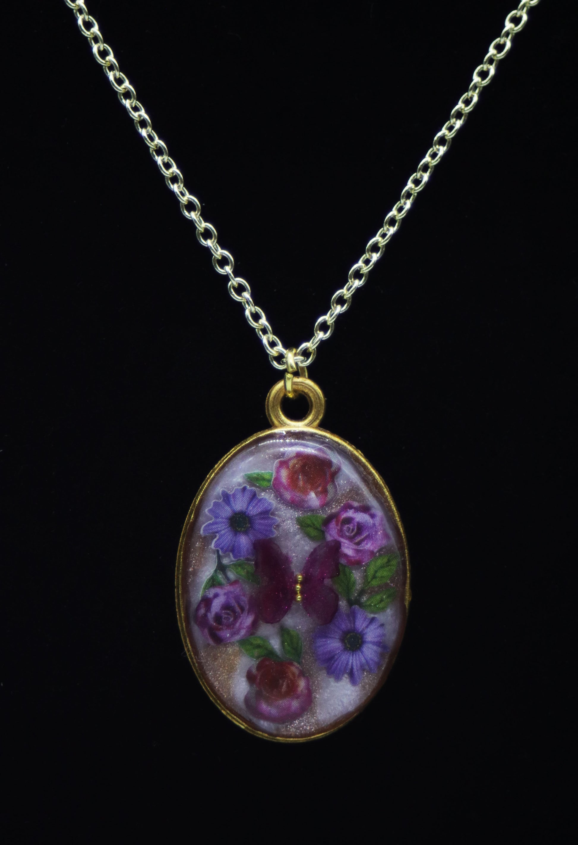 Gold oval resin necklace with purple botanical flowers on lavender shimmer background