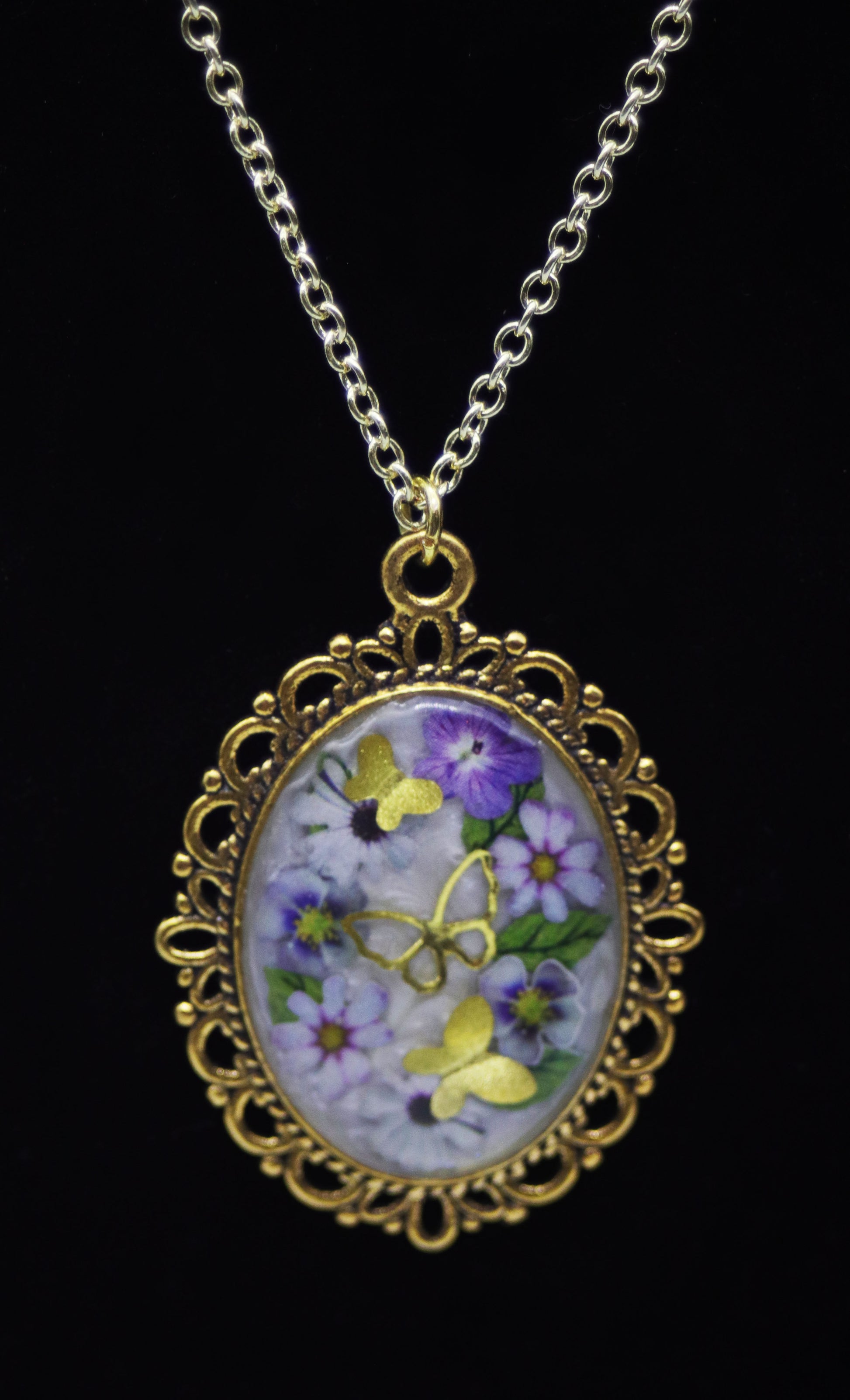 Gold oval domed resin necklace with purple pansies, lavender daisies, and gold butterfly accents