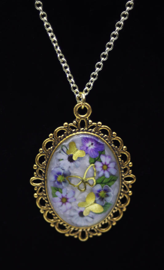 Gold oval domed resin necklace with purple pansies, lavender daisies, and gold butterfly accents