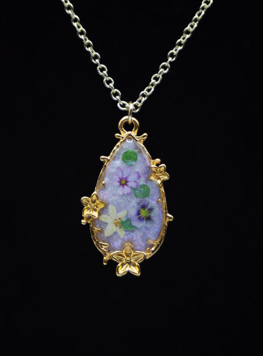 Delicate gold teardrop resin necklace with flower charm border and purple pansy garden interior