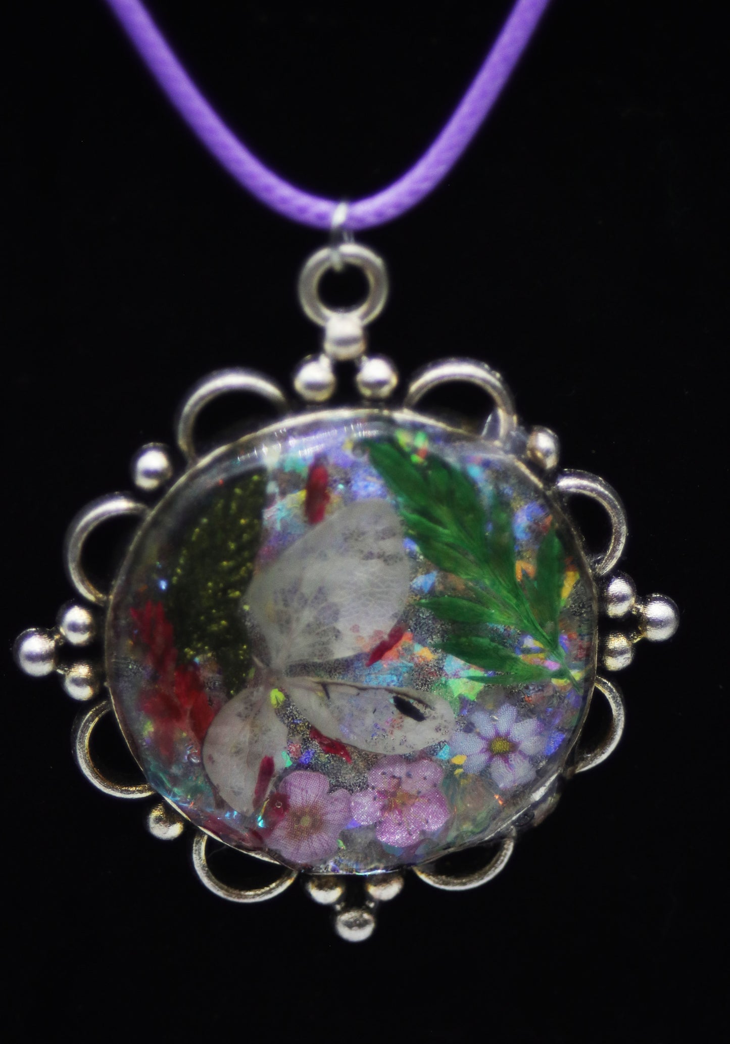 Silver scallop round resin necklace with layered pressed flowers and holographic glitter on purple cord