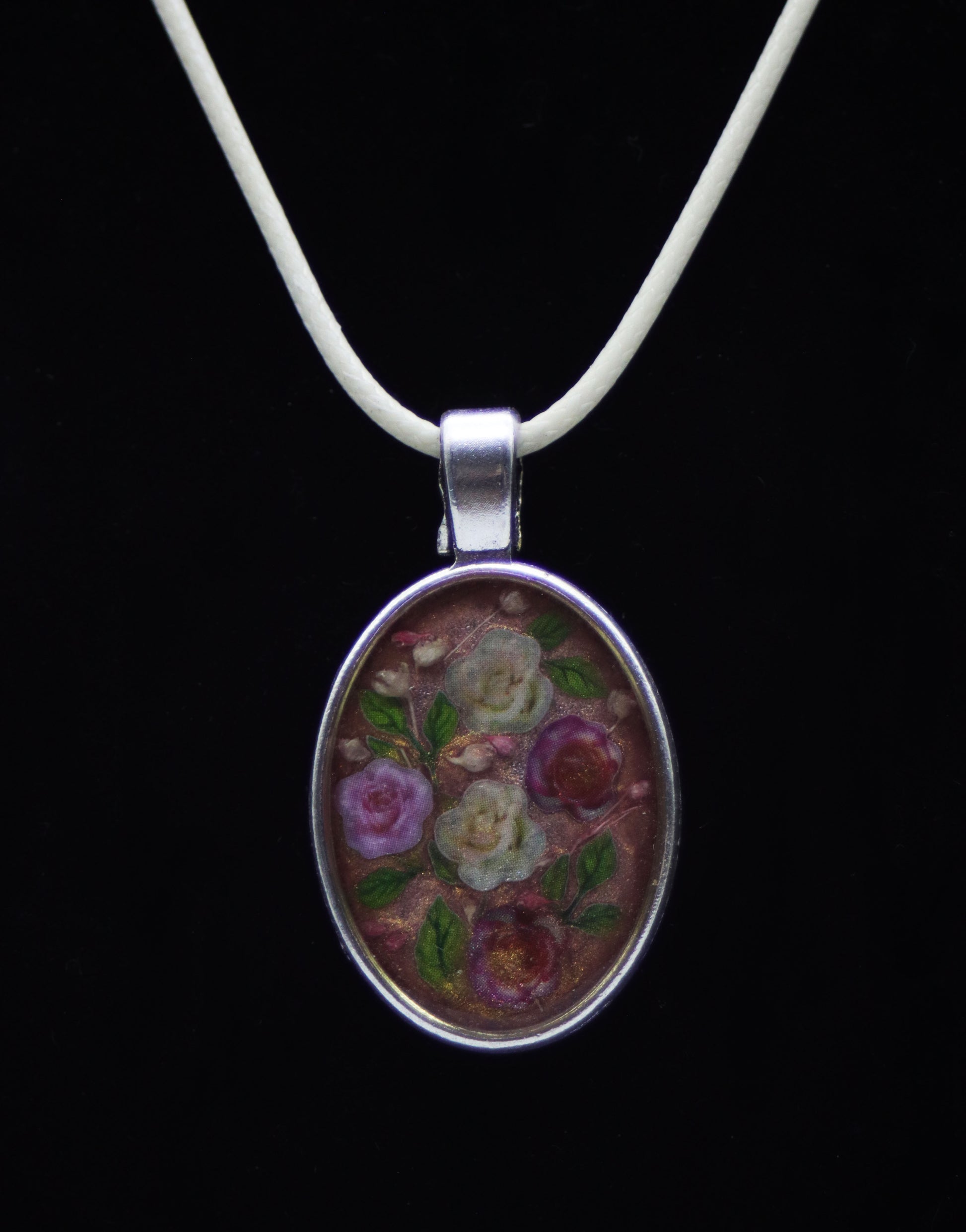 Silver oval resin necklace with wood flower roses in purple, cream, and red on ivory cord