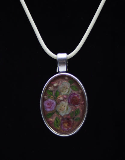 Silver oval resin necklace with wood flower roses in purple, cream, and red on ivory cord