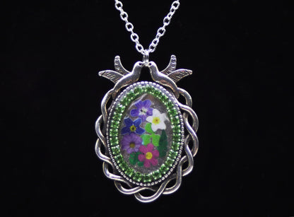 Silver Celtic oval resin necklace with two dove charms, green rhinestones, and colorful wood flowers
