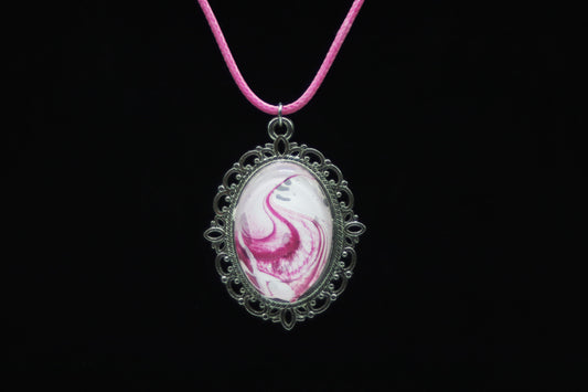 Silver filigree oval necklace with glass cabochon over hot pink and white swirl paint skin on pink cord