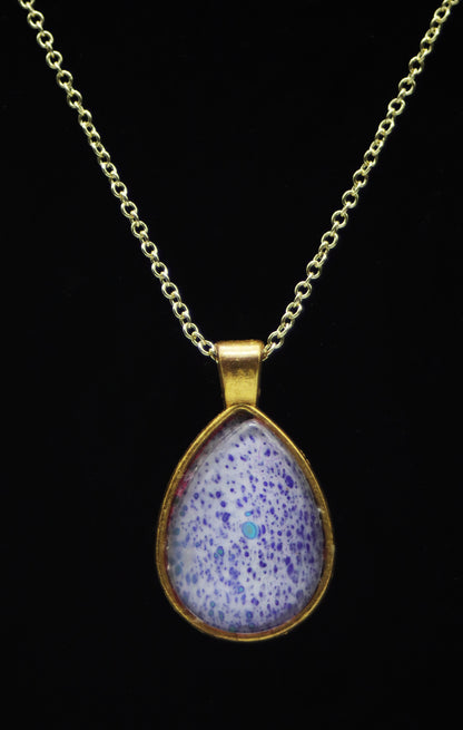 Gold teardrop necklace with glass cabochon over lavender periwinkle purple speckle paint skin