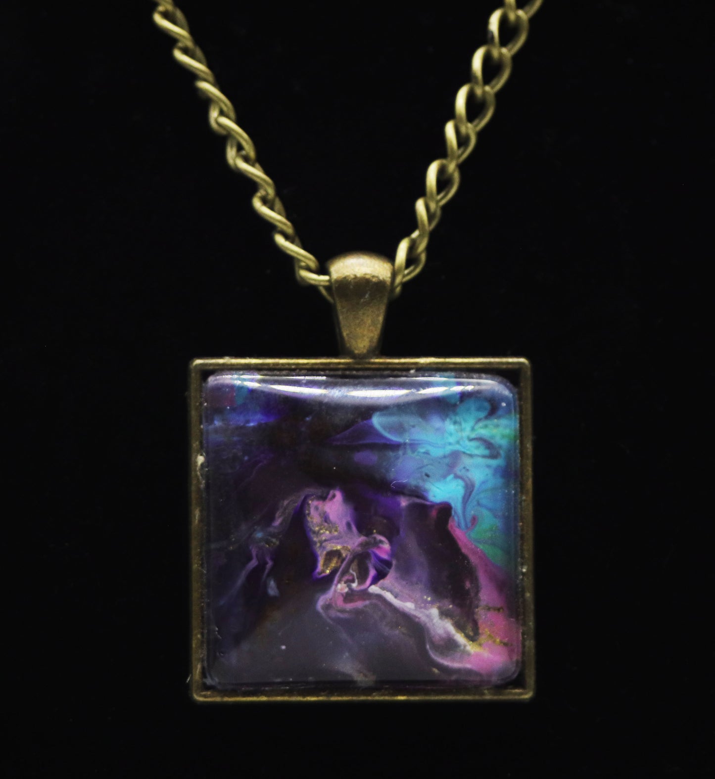 Antique gold square necklace with glass cabochon over deep purple black galaxy paint skin with teal and pink swirls