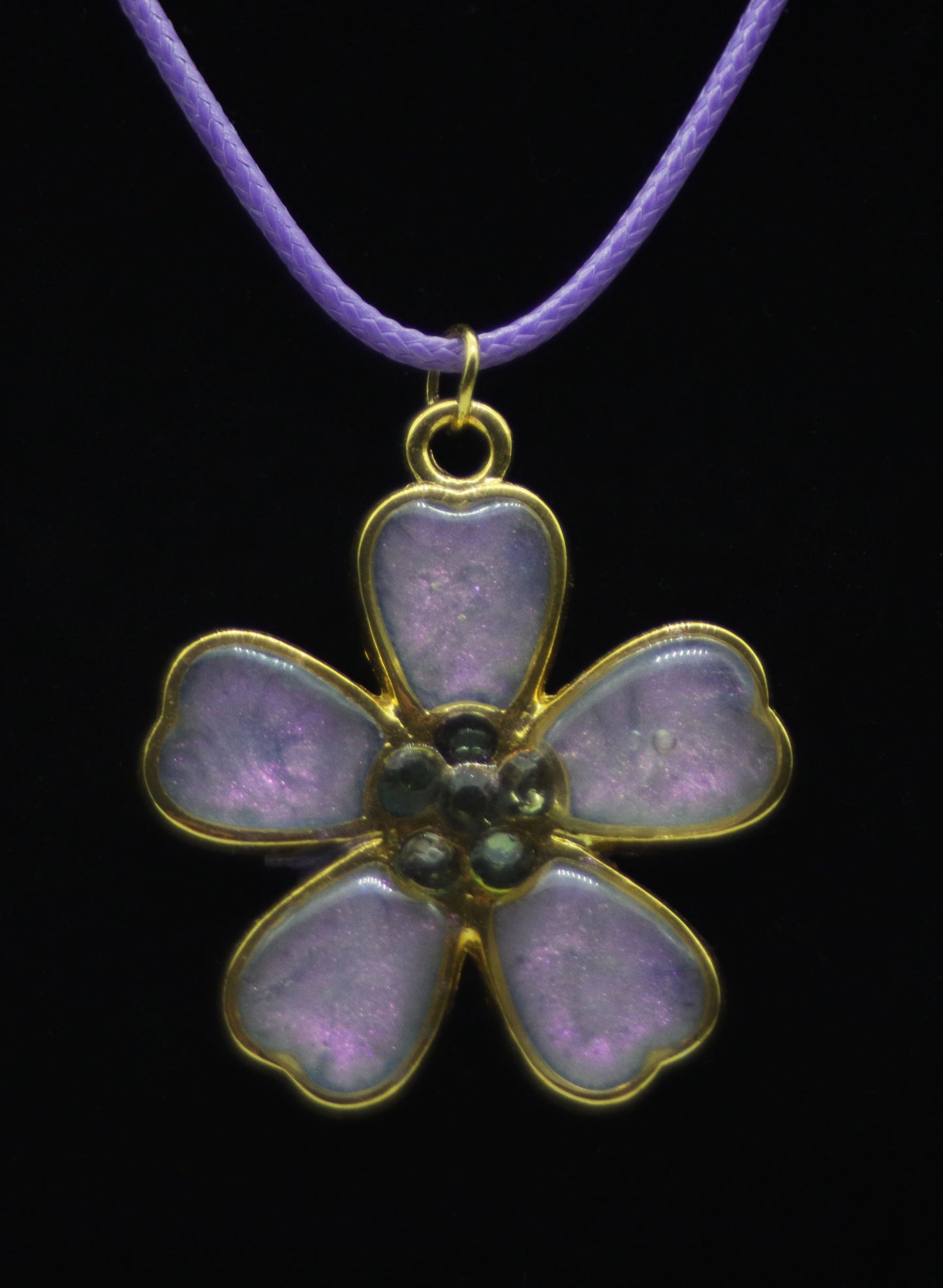 Gold five-petal flower necklace with lavender resin petals and dark teal bead center on lavender cord