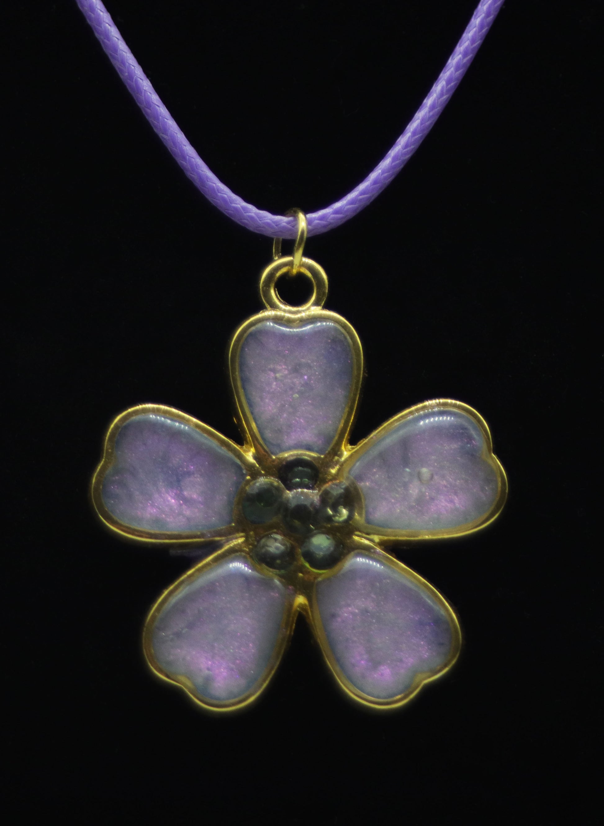 Gold five-petal flower necklace with lavender resin petals and dark teal bead center on lavender cord