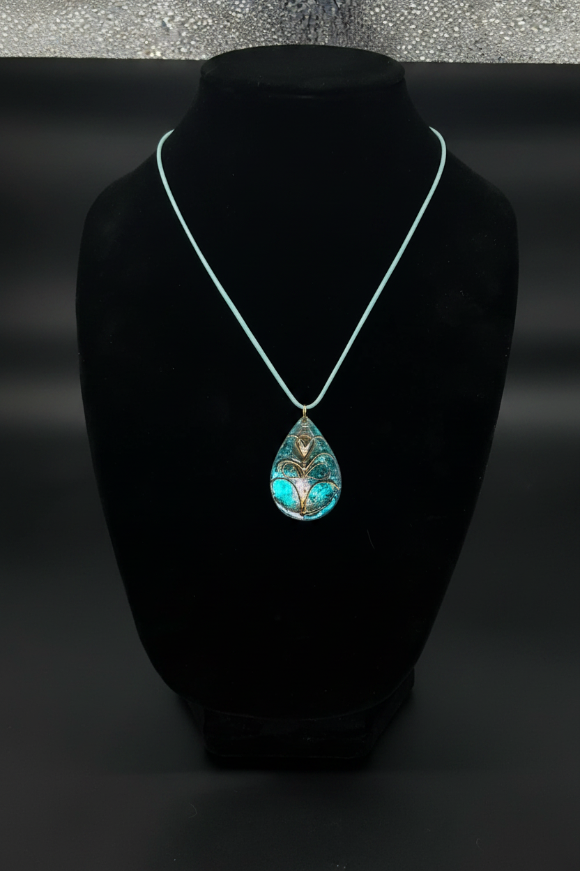 Handmade teal teardrop resin necklace with gold floral detail on white cord